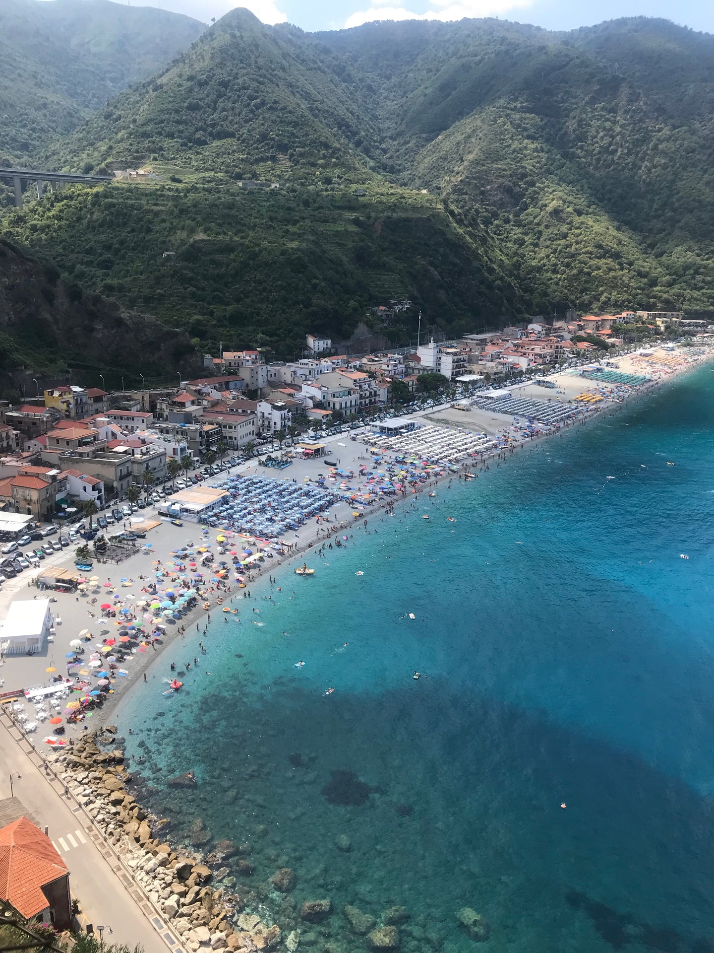 beautiful beach in Calabria showing aqua water meeting the contrast of rugged hills of greenery
